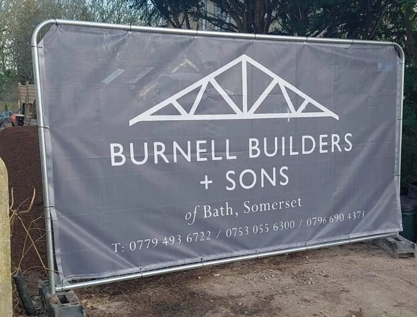 Large grey Burnell Builders and Sons outdoor banner attached to a metal frame