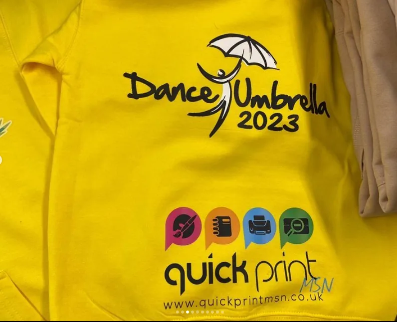 Yellow Dance Umbrella 2023 shirt printed with black artwork and the Quickprint MSN logo